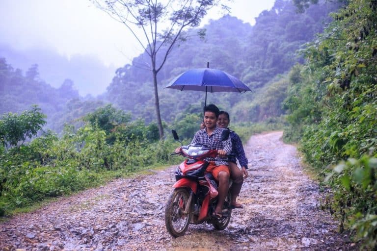 two locals riding with an umbrella