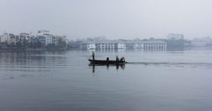 men on a boat on Westlake, on a smoggy day in Hanoi