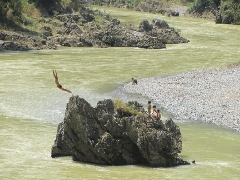 children jump from boulders into the muddy waters of the Mien River