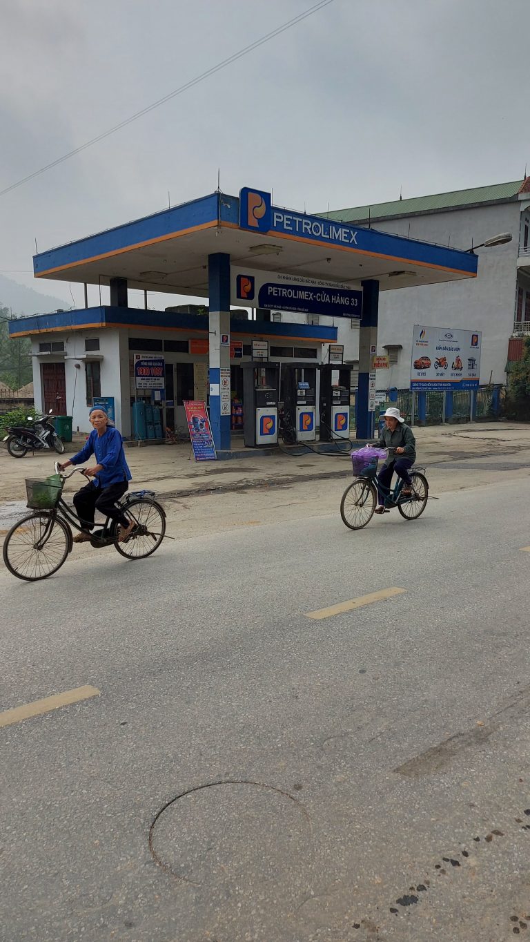two women cycling past a petrol station in cao bang