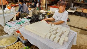 a woman selling dau phu / tofu in bao lac market ha giang