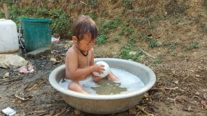 a little girl having a bath in a bowl
