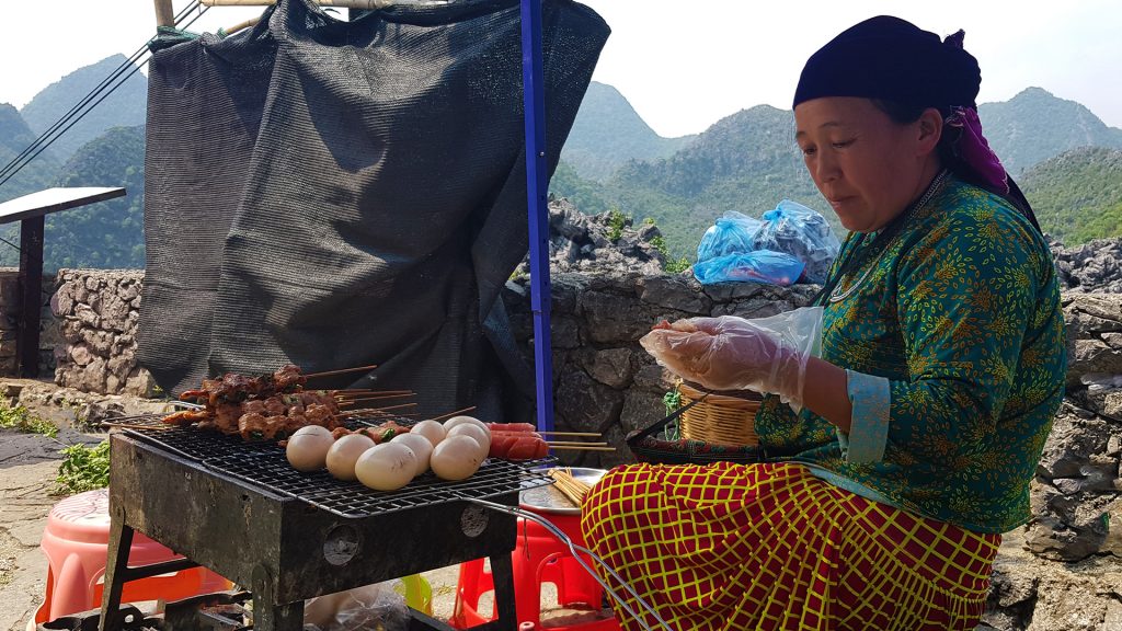 local woman cooking meat and eggs up in Dong Van