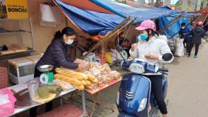 a young woman buying bread from a local seller in Bac Son market, lang son.