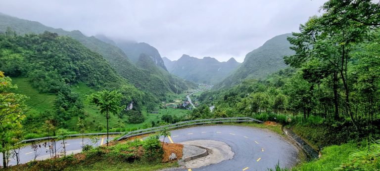 a road winding its way down to the valley in Ha Giang