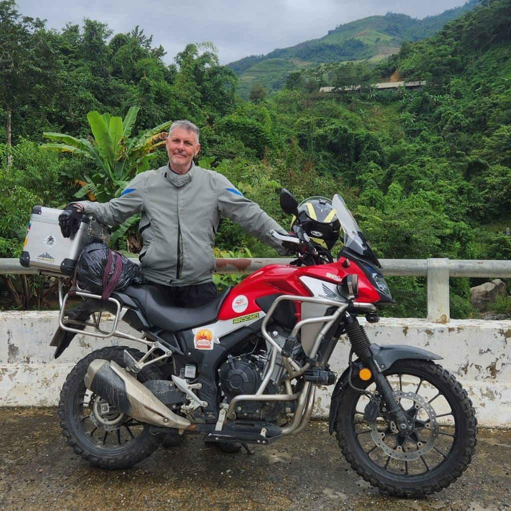 Rentabike tour member and his Honda CB with Laos in the background