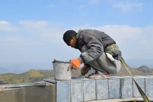 a guy repairing the wall on top of the lung cu flagpole