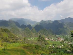a view out over the mountains of ha giang and a small village nestled in the valley below