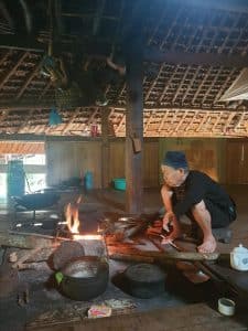 grandmother cooks dinner on a basic open fire in a stilt house in ha giang