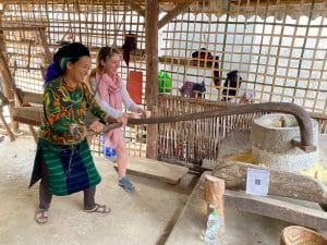 helping with the daily chores, grinding corn, in a family homestay in ha giang