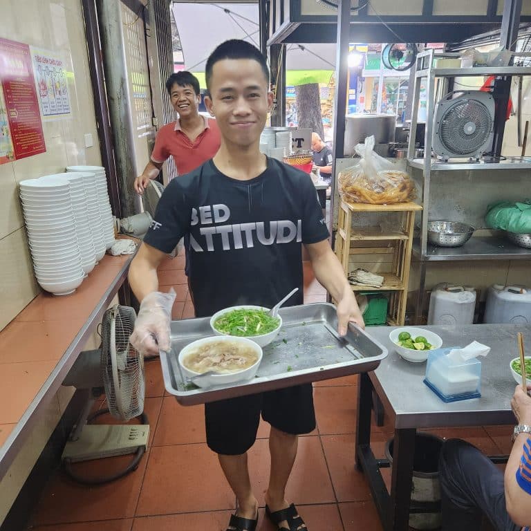 A young server holding a tray of Pho local Pho shop