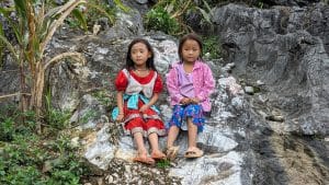 ethnic girls sitting on a rock in ha giang