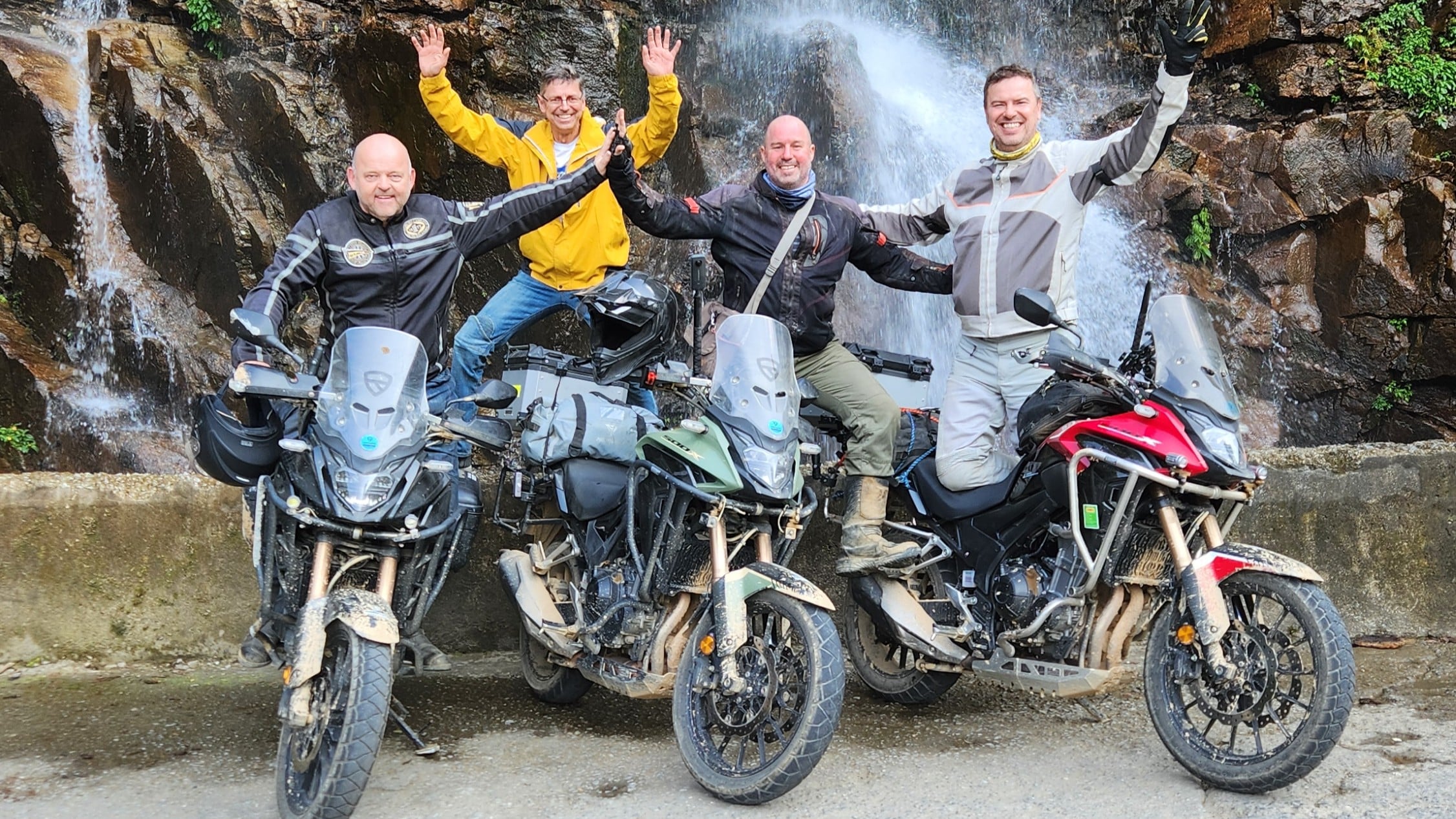 a happy group of riders in ha giang on the 10 day due north tour with rentabike vietnam at a waterfall on the honda cb500x