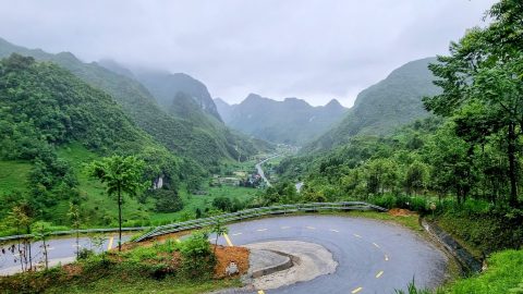 a road winding its way down to the valley in Ha Giang