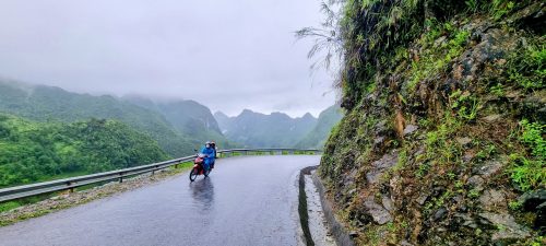 riders in the rain coming around a corner in Ha Giang